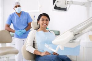 A smiling patient in a dental chair with a dentist nearby, in a bright, clean clinic setting.