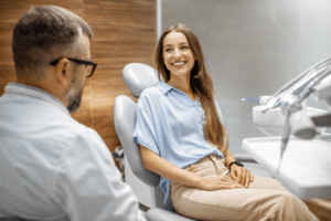 A smiling, calm patient sitting in a dental chair, chatting with a dentist