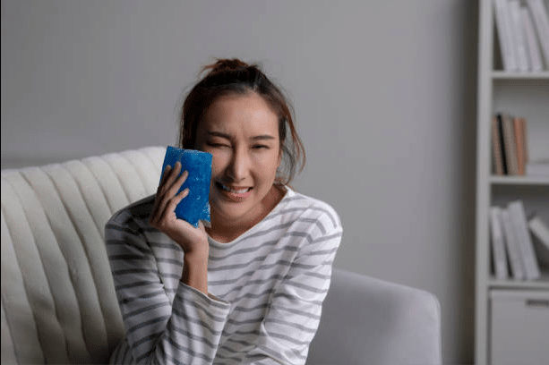 Patient using ice pack after wisdom tooth removal for swelling